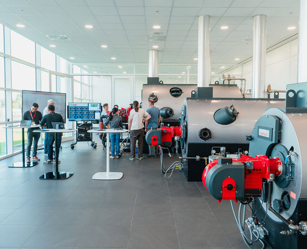 Group of people in a modern industrial setting with large machinery and screens.