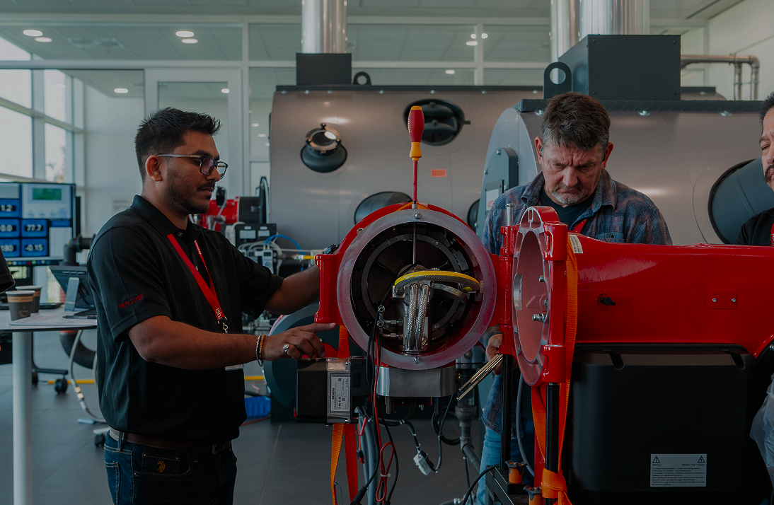 Two men working on a large piece of machinery in an industrial setting