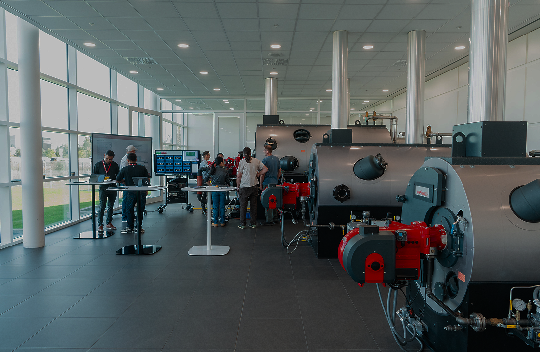 Group of people in a modern facility with large windows, observing equipment.